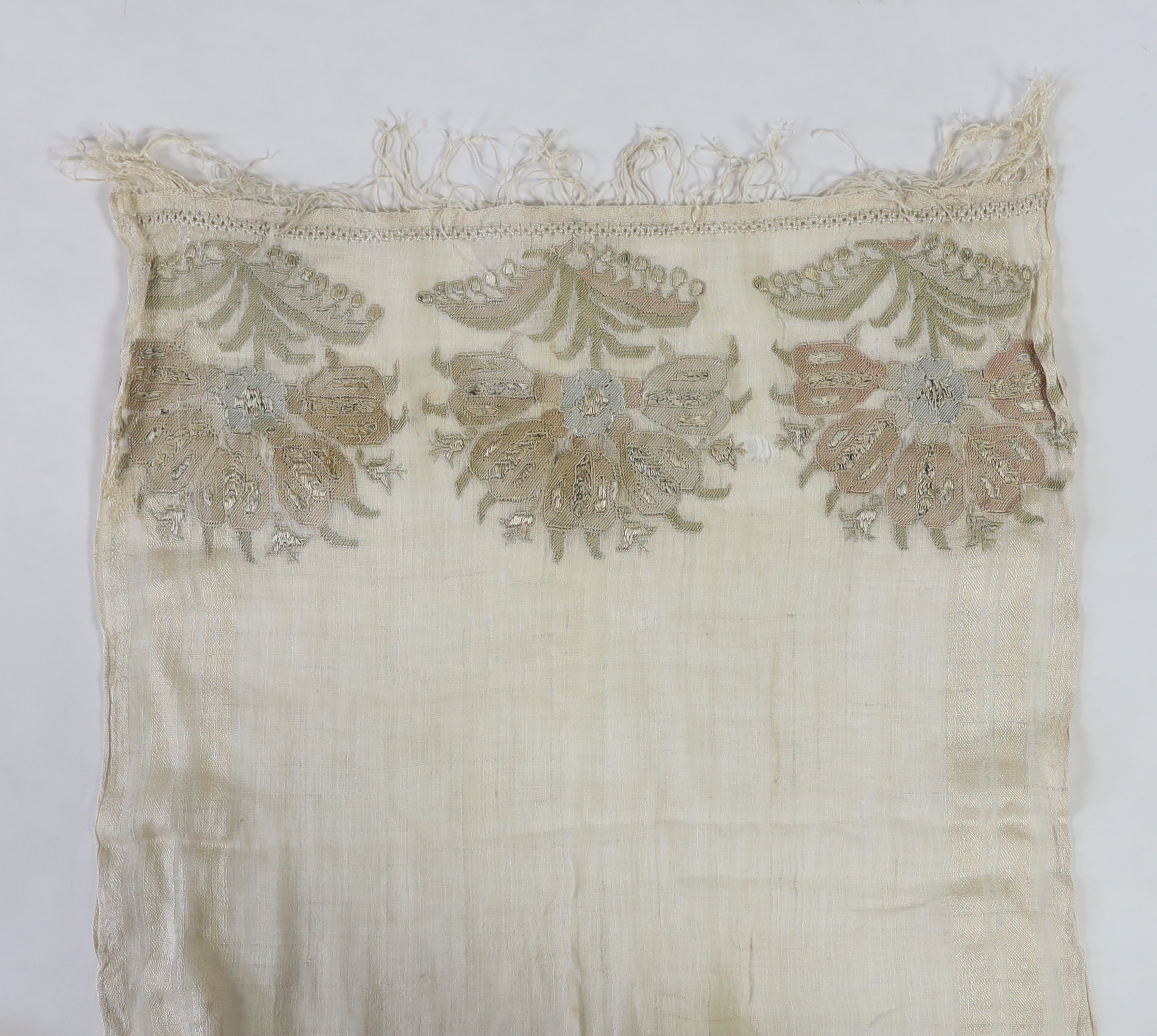 A 19th century Turkish towel, embroidered with flower motifs, in pastel shades, with fine silk fringing embroidered onto a fine hand spun linen, woven with stripes to each side, 48cm wide, 120cm long